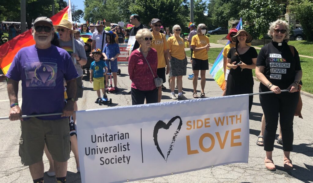 Reverend Diana and members of UUS standing with a "side with love" sign during the 2022 Iowa City Pride parade.